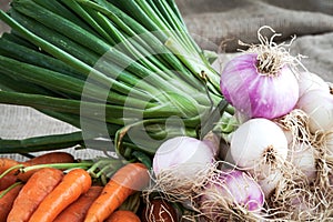 Carrots and onions on table background and woven sack