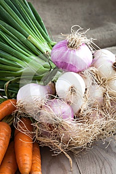 Carrots and onions on table background and woven sack