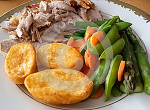Carrots and snap peas on a plate with roast pork and roast potatos