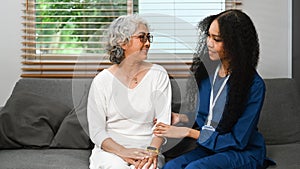 Carrying female doctor talking senior patient during a home visit. Elderly healthcare and Home health care service