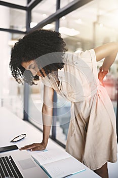 Carrying her tension in her lower back. a young businesswoman experiencing back pain while working in a modern office.