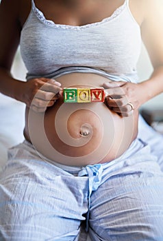 Carrying a little prince. a pregnant woman with wooden blocks on her belly that spell the word boy.