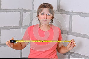 Carrying out independent uncertain measurements in the repair of a new apartment. The young woman herself distressed measures the