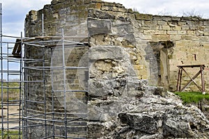 Carrying out restoration work in the ancient medieval fortress. Metal scaffolding is installed next to the old wall