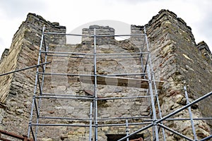 Carrying out restoration work in the ancient medieval fortress. Metal scaffolding is installed next to the old wall to work