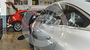 cars in auto repir shop, side view of a silver car and a red car in front of it