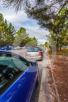 Cars or automobiles parked over the curb into sidewalk, leaving no space for pedestrians in the walkway. Road accessing a suburban