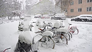 Cars and bikes covered in snow during heavy snowfall