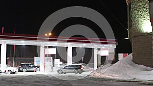 Cars come to petrol station and refuel at night in winter