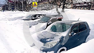 Cars covered in snow parked on parking lot in winter season. Parked car covered with snow after blizzard. Car buried