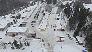 Cars drive along the country road to the parking of a winter ski resort aerial.