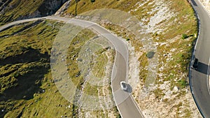 Cars drive on asphalt highway curve in high Italian Alps