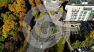 Cars drive at cross road in the city with autumn trees. Highway transportation