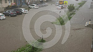 Cars drive on a flooded road in a downpour.