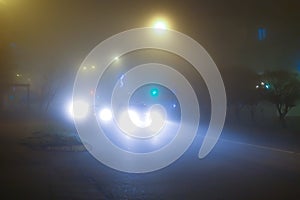 Cars drive at night in fog. Headlights of cars illuminate the fog