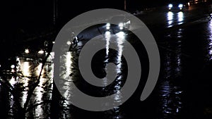 Cars drive on a night road in the rain. Cars on the night city highway. Reflection of car headlights on wet pavement. Cars