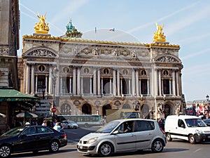 Cars drive past Palais Garnier opera house, Paris, France