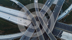 Cars driving along freeway go to exits from multi-level interchange. Top view from drone. Modern design of American