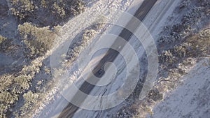 Cars driving along the winter road with snow covered trees aerial view