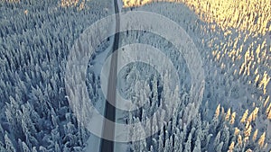 Cars driving on a highway in a snow covered winter landscape.