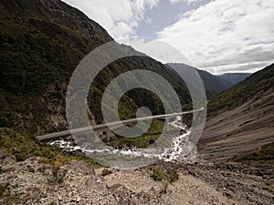 Cars driving on Otira Viaduct concrete bridge over green alpine valley river at Arthurs Pass Southern Alps New Zealand