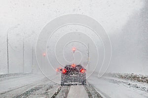 Cars driving on road in snowfall.Blur focus.Concept of snowy winter, danger of accidents, careful driving