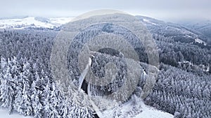 Cars driving through the snowy forest. Panoramic winter drone view of the mountains in the forest.