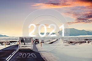 A cars driving to 2021 in winter, with 2020 on the road in sunrise. New Year concept