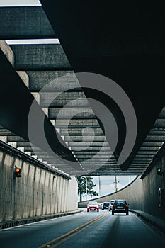 Cars driving on in a tunnyl under bridge with roof trusses