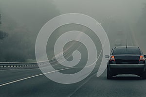 Cars in fog driving on highway in dangerous weather. Bad low visibility and auto traffic on road. Vehicles in haze on freeway