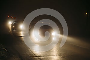 Cars in a fog during night with shining headlights