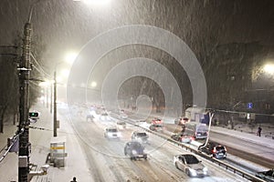 Cars on highway in blizzard. Winter in the city. Traffic jam and traffic camera at night. Cold snowy weather in town