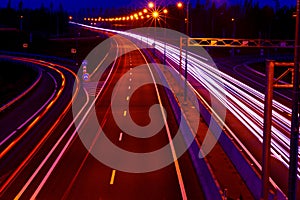 Cars light trails on a curved highway at night. Night traffic trails. Motion blur. Night city road with traffic headlight motion.