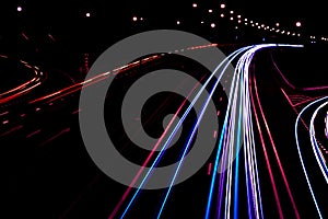 Cars light trails on a curved highway at night. Night traffic trails. Motion blur. Night city road with traffic headlight motion.