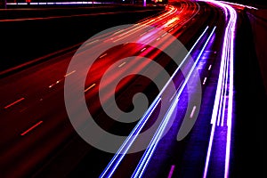 Cars light trails on a curved highway at night. Night traffic trails. Motion blur. Night city road with traffic headlight motion.