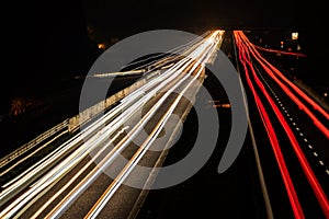 Cars light trails at night in curve asphalt road. Long exposure showing the movement of traffic from the bridge