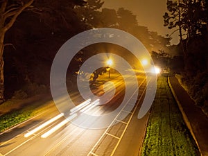 Cars in motion on a dark park street with safety and biking danger warnings