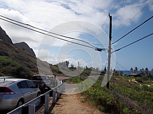 Cars parked along cliffside mountain highway at Makapuu with stretching blue pacific ocean
