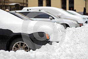 Cars parked on a side of city street covered with snow in winter