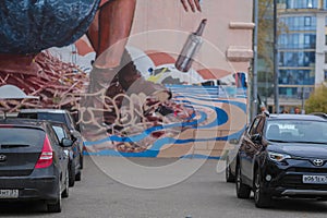 Cars on the parking in front of the wall of the house with graffiti in Moscow