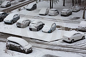 Cars in the parking lot under the snow. Snowfall