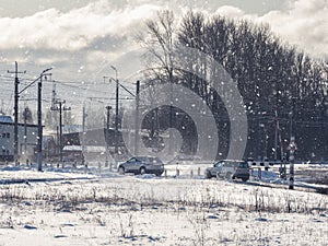 Cars pass a railway crossing outside the city in winter.