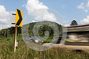 Cars passing signpost bends.