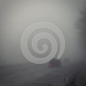 Cars on the road in the fog. Autumn and winter concept of dangerous traffic in bad weather. Car lights in bad visibility