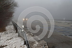 Cars on the road in the fog. Autumn and winter concept of dangerous traffic in bad weather. Car lights in bad visibility