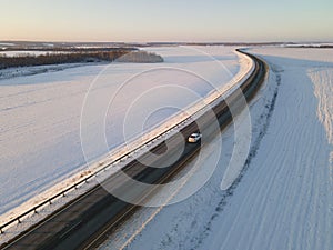 Cars on the road surrounded by winter fields. Aerial view