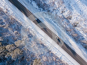 Cars on road in winter with snow covered trees aerial view