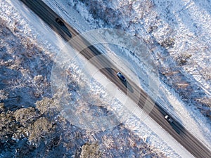 Cars on road in winter with snow covered trees aerial view