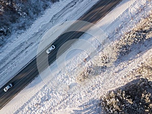 Cars on road in winter with snow covered trees aerial view