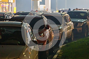 cars stuck in traffic jam at gas station at foggy night during supply crunch